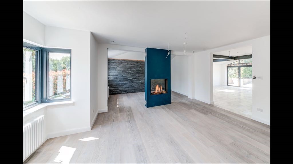 The living area at Pampisford Road during finishing works, with a central fireplace and views through to the extension