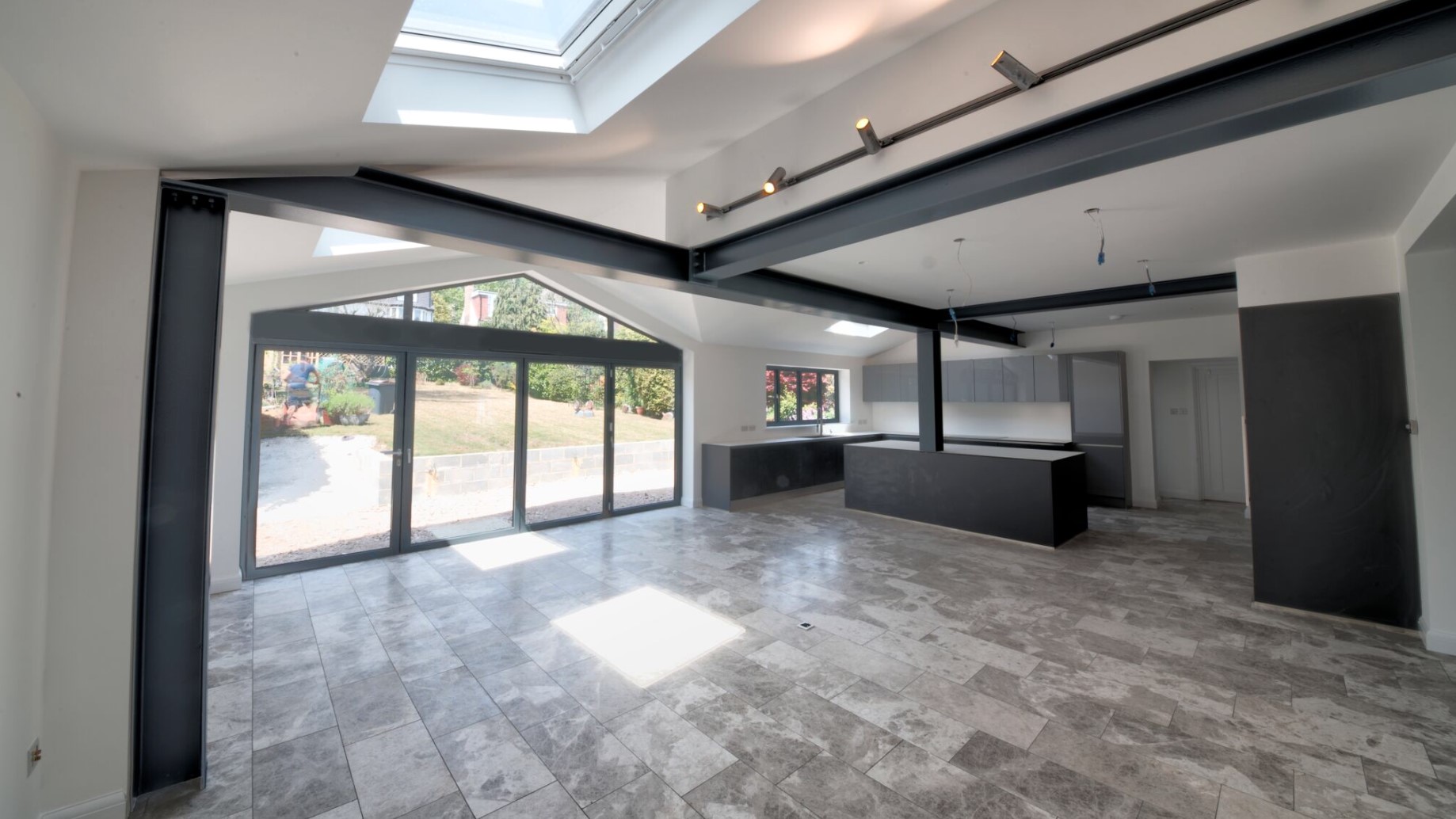Open-plan kitchen extension on Pampisford Road during fit-out, with exposed steel beams, rooflights and glazed doors to the garden